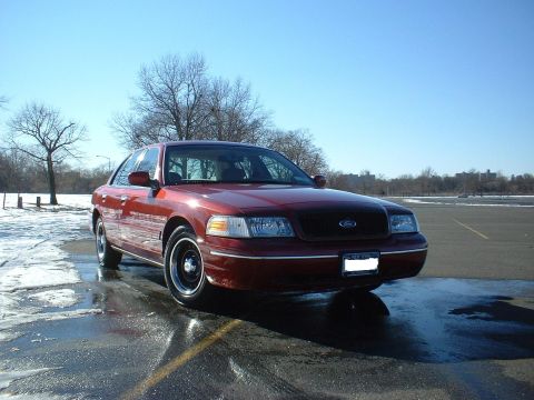 1999 Ford Crown Victoria - A red Ford Crown Victoria is parked outside on a cold, sunny day with patches of snow on the ground.
