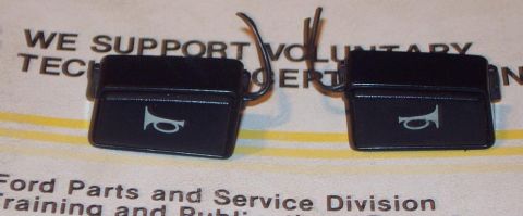 1985 Ford LTD Crown Victoria - Two horn buttons, likely for a Ford vehicle, are shown against a document.