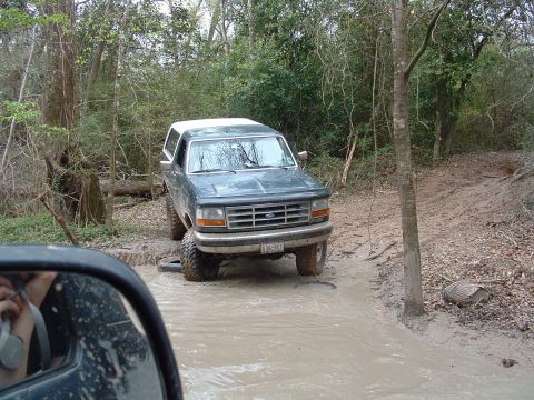 1993 Ford Bronco - A 1993 Ford Bronco navigates a challenging muddy off-road path.