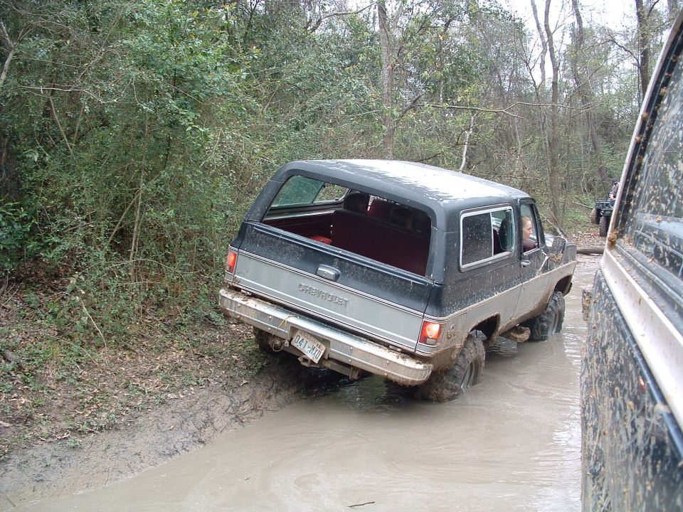 Chevy K5 Blazer driving through mud, another vehicle visible on the right