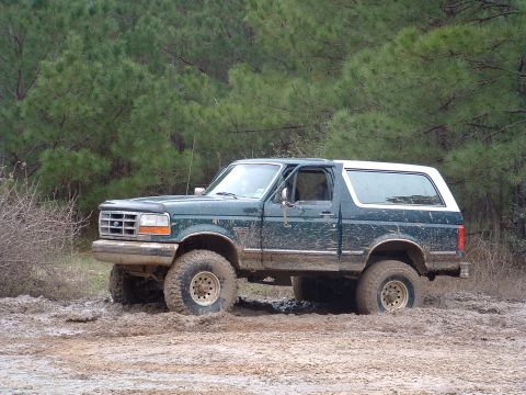 1993 Ford Bronco - This Ford Bronco is deep in the mud, with trees in the background.