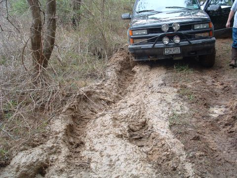 1993 Ford Bronco - SUV struggling through thick mud on an off-road trail, with another vehicle nearby.