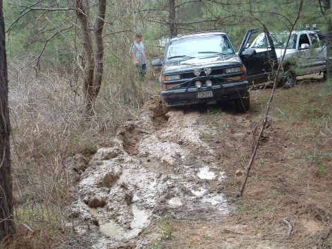 1993 Ford Bronco - Two SUVs navigate a muddy trail, one appears to be stuck.