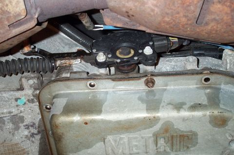 1998 Ford Crown Victoria - Underside view of a transmission showing the shift linkage and range sensor mounted on top, with the manual shift lever and cable connectio…