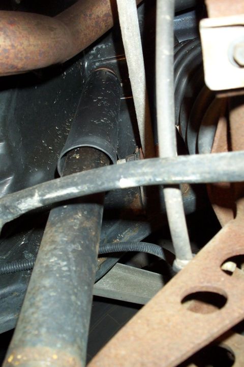 1998 Ford Crown Victoria - Close-up underside view of a vehicle's suspension and undercarriage, showing a black rubber shock absorber boot/dust cover, coil spring, va…