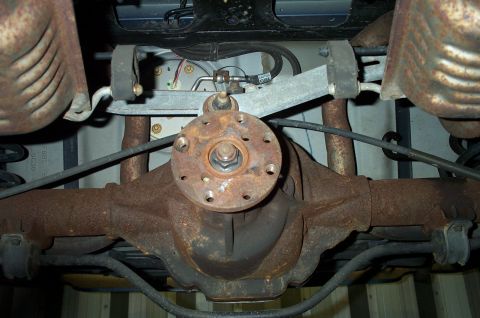 1998 Ford Crown Victoria - Underside view of a rear solid axle differential, heavily surface-rusted, with the pinion flange, hub and driveshaft yoke visible at center…