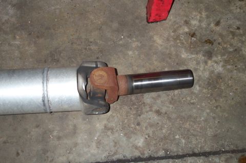 1998 Ford Crown Victoria - Close-up of a driveshaft's slip yoke and universal joint, showing a polished splined output shaft, a rusty U-joint cap, and a metal yoke, l…