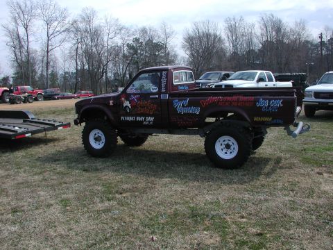 1985 Ford Bronco - A heavily modified pickup truck with custom paint and graphics sits on a grassy field.