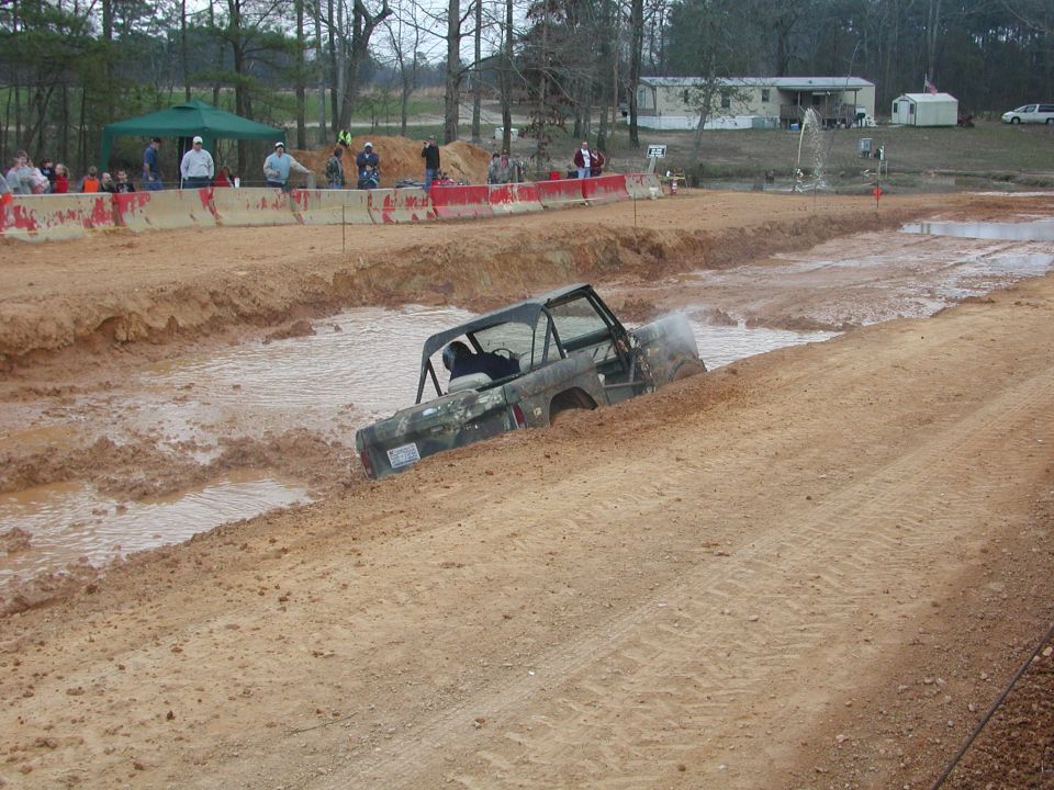 Camouflaged Ford Bronco navigating a mud pit