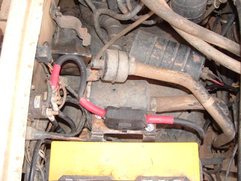 1990 Ford Bronco - Wiring and components in the engine bay, including a battery and alternator, are visible in this close-up shot.