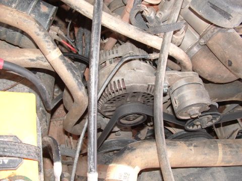 1990 Ford Bronco - The image shows an alternator and its associated belts within an engine bay, with no clear indication of the vehicle's make or model year.