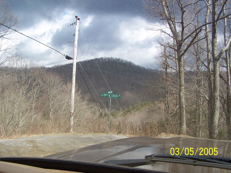 Dashboard view from inside a vehicle looking out at a rural landscape with a Tipton Creek road sign