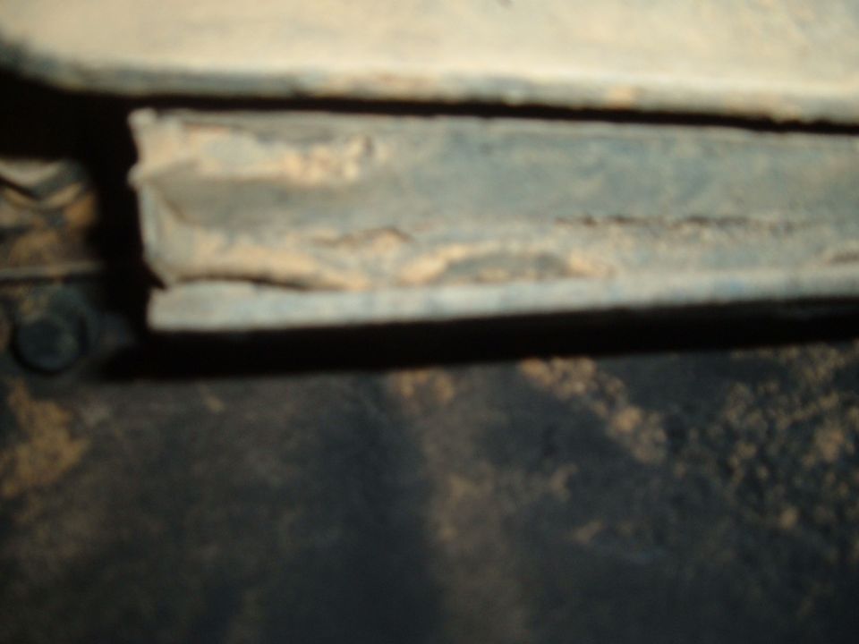 Close-up of a dirty metal frame with visible rust and dirt accumulation