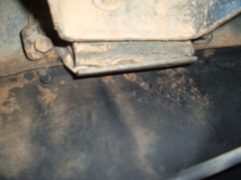 1978 Ford Bronco - Close-up of a rusty metal bracket attached to a vehicle frame, likely from the undercarriage.