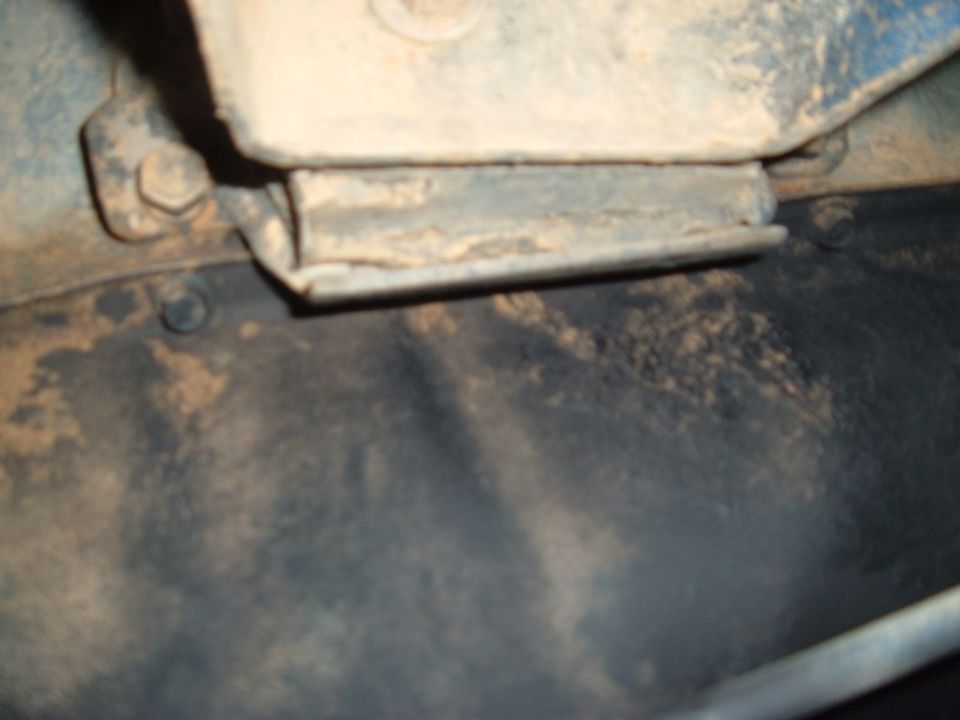 Close-up of a rusty metal bracket attached to a vehicle frame