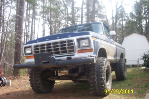 1979 Ford F-150 - A lifted 1979 Ford F-150 pickup truck with a blue and white paint scheme sits in a wooded area.