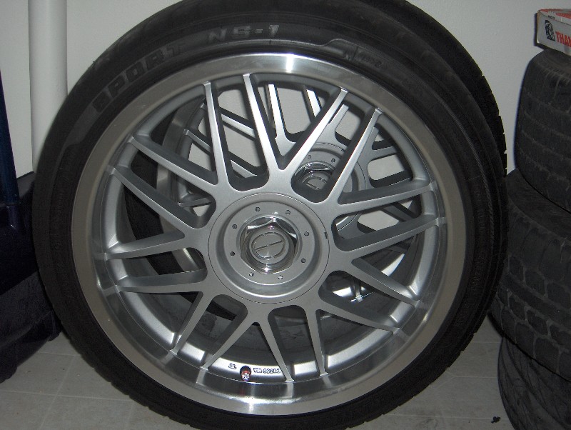 Silver mesh-spoke aftermarket wheel on a low-profile tire, indoors