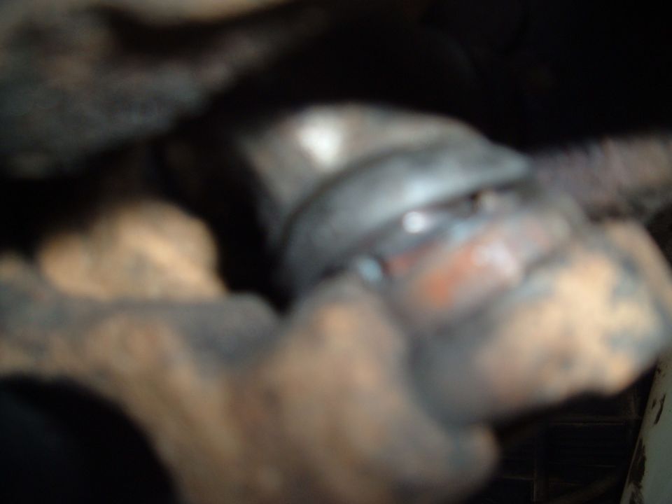 Close-up of a dirty, metallic vehicle suspension part with orange accents