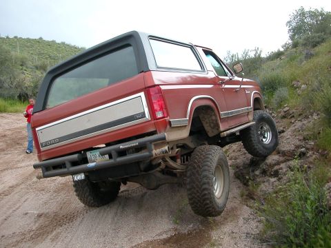 1984 Ford Bronco - This lifted 1984 Ford Bronco navigates a steep, rocky incline on a dirt trail.