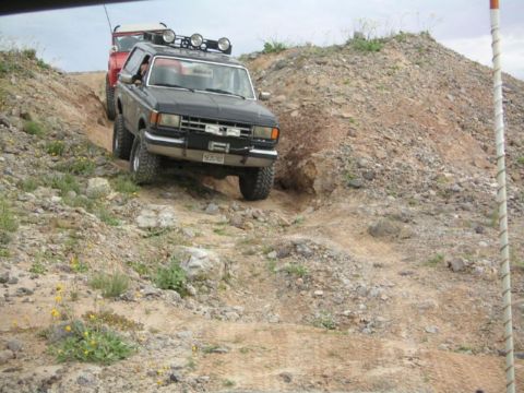 1988 Ford Bronco - Two off-road vehicles navigate a steep, rocky incline on a dirt trail.