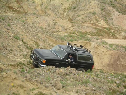 1988 Ford Bronco - This 1988 Ford Bronco navigates a challenging off-road terrain, its capabilities with added roof rack and lights.