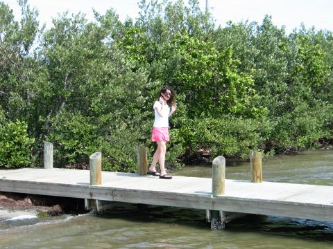 1995 Nissan Frontier - A woman walks along a wooden pier surrounded by lush green foliage and calm water.