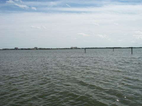 1995 Nissan Frontier - A wide view of water with a distant cityscape and posts in the water under a cloudy sky.