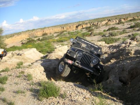 1988 Ford Bronco - Jeep CJ-7 tackles a challenging off-road course with steep inclines and rough terrain.