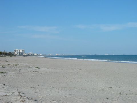 1995 Nissan Frontier - A beach scene with buildings lining the coast and the ocean under a clear blue sky.