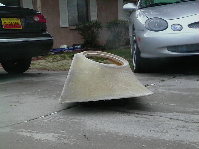 Fiberglass part in driveway with two cars parked nearby