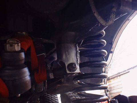 1988 Ford Bronco - Underside view of a vehicle's suspension system, focusing on the coil spring and mounting hardware.