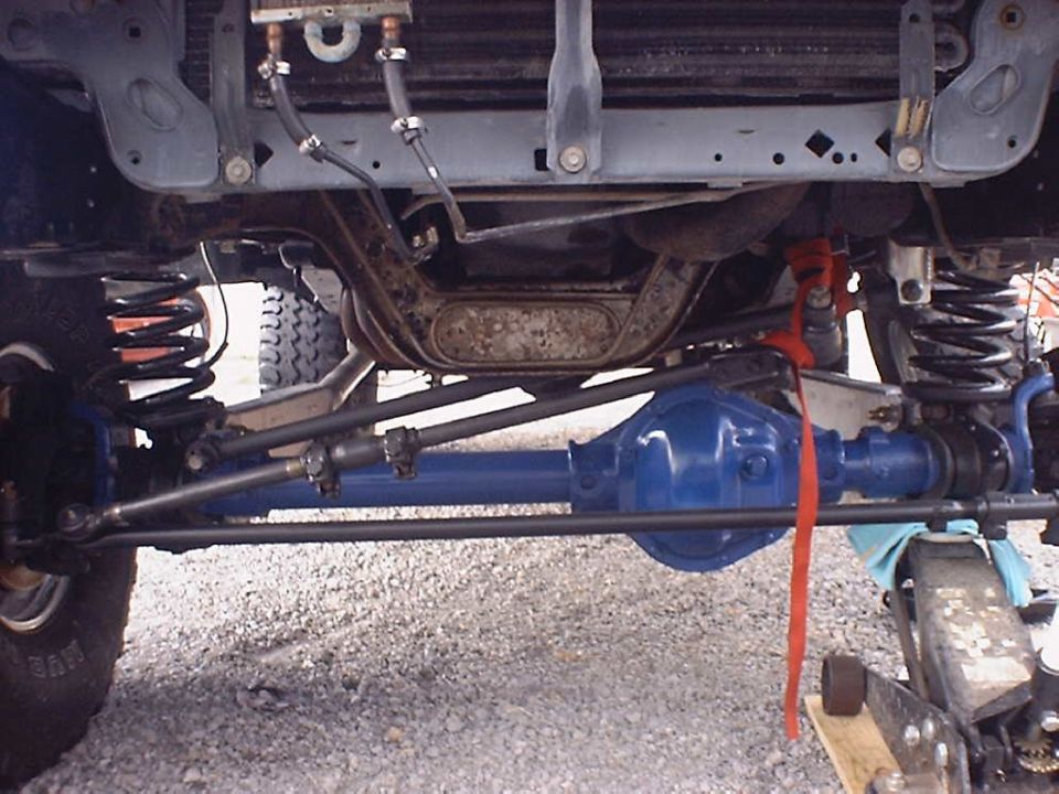 Underside view of a vehicle's front axle and suspension, with blue-painted differential and black steering components