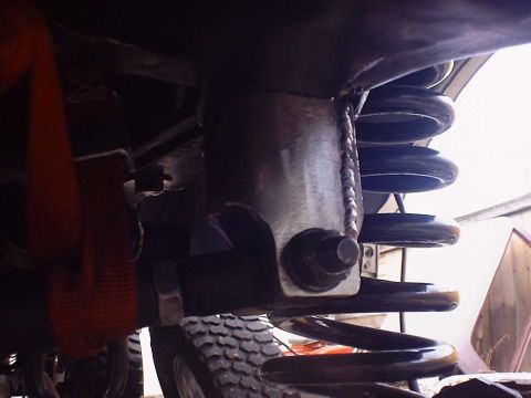 1988 Ford Bronco - Underside view of a vehicle's suspension system, focusing on the coil spring and its mounting hardware.