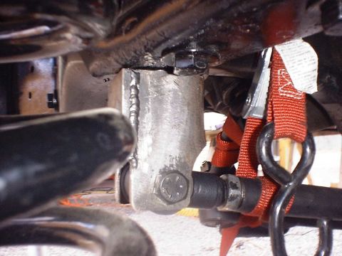 1988 Ford Bronco - Welded suspension part with red strap and metal ring, likely from a vehicle's undercarriage.