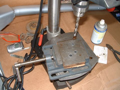 1995 Ford Bronco - A drill press is set up with a vise to hold a metal piece for drilling, surrounded by various tools and safety equipment.