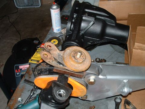 1995 Ford Bronco - Various automotive parts, including a differential and suspension components, are laid out on a workbench.