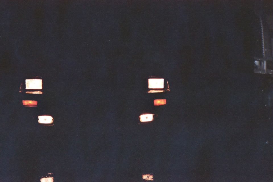 Night front view of a car with headlights, amber markers and parking lamps lit in darkness