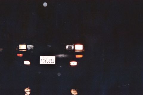 1985 Ford Mustang - A car's rear end is illuminated at night, with its license plate clearly visible.