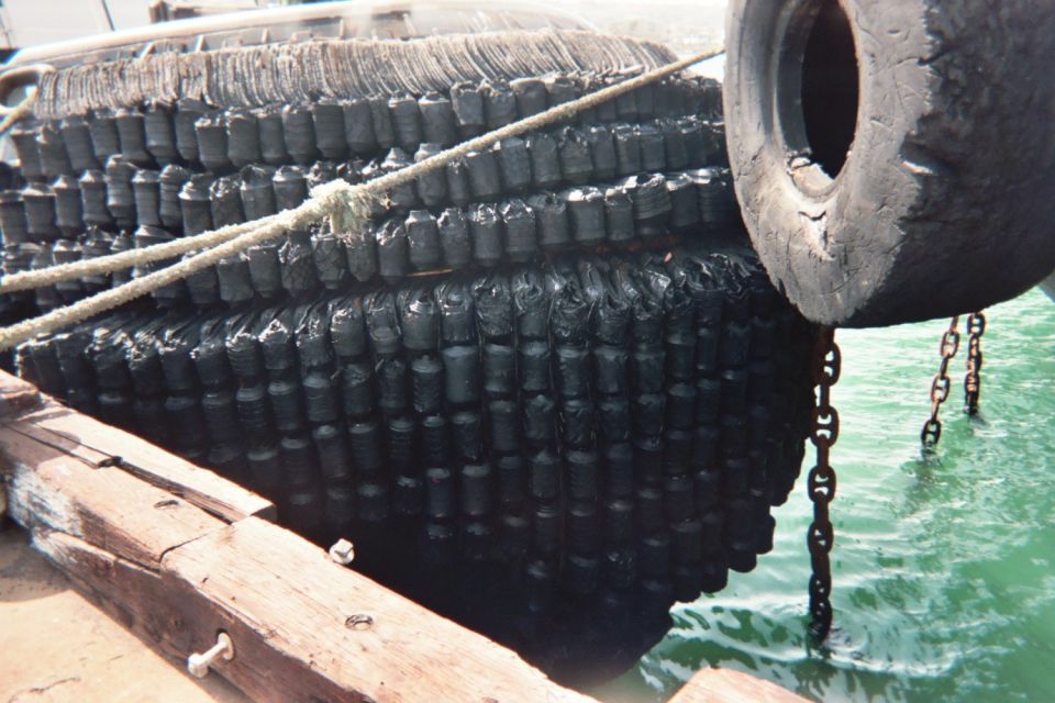 Tire-covered marine fender on the hull of a vessel at a dock with chains