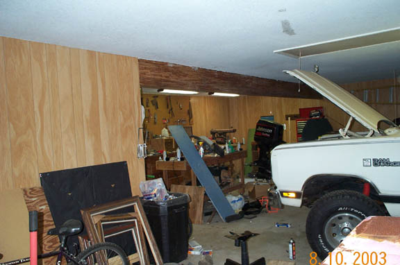 White pickup truck with hood open in a cluttered garage. "RAM CHARGER" text visible on fender