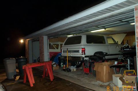 1996 Ford Bronco - Two vehicles are parked inside a garage at night, with one SUV prominently displayed.
