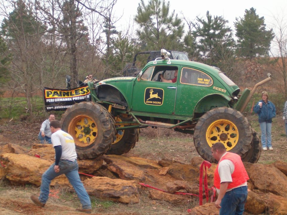 Green and yellow John Deere-themed VW Beetle rock crawler climbing rocks at an event