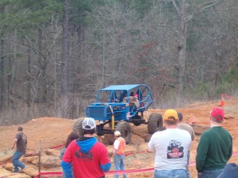 1996 Ford Bronco - A custom-built off-road buggy navigates a challenging dirt course with spectators observing.