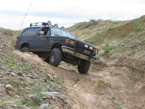 1988 Ford Bronco - This Ford Bronco is navigating a steep, rocky incline on a dirt trail.