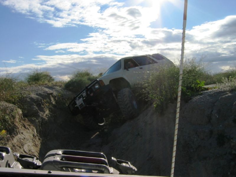 1988 Ford Bronco climbing a steep dirt hill, another vehicle visible in foreground
