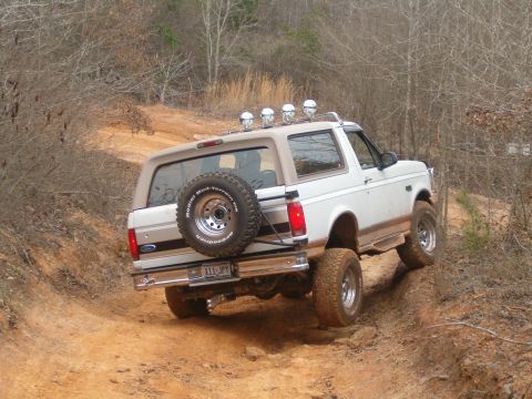 1996 Ford Bronco - This 1996 Ford Bronco is navigating a challenging off-road trail with its spare tire mounted externally.