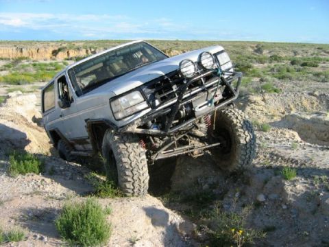 1988 Ford Bronco - Modified 1988 Ford Bronco tackling a challenging off-road course on a sunny day.
