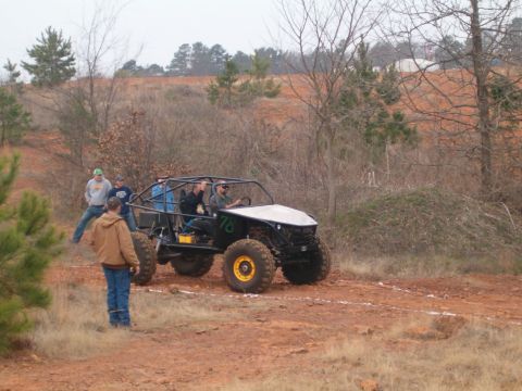1996 Ford Bronco - A custom off-road buggy with a roll cage and large tires is being observed by several people on a dirt path.