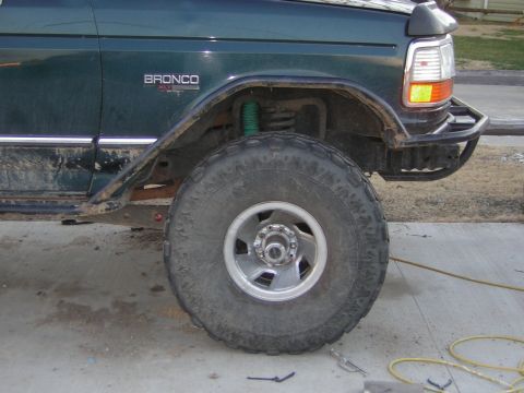 1995 Ford Bronco - Side view of a green 1995 Ford Bronco, large off-road tires and a custom front bumper.