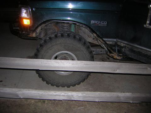 1995 Ford Bronco - The side of a green Ford Bronco is visible, with a large tire and part of the fender and door.